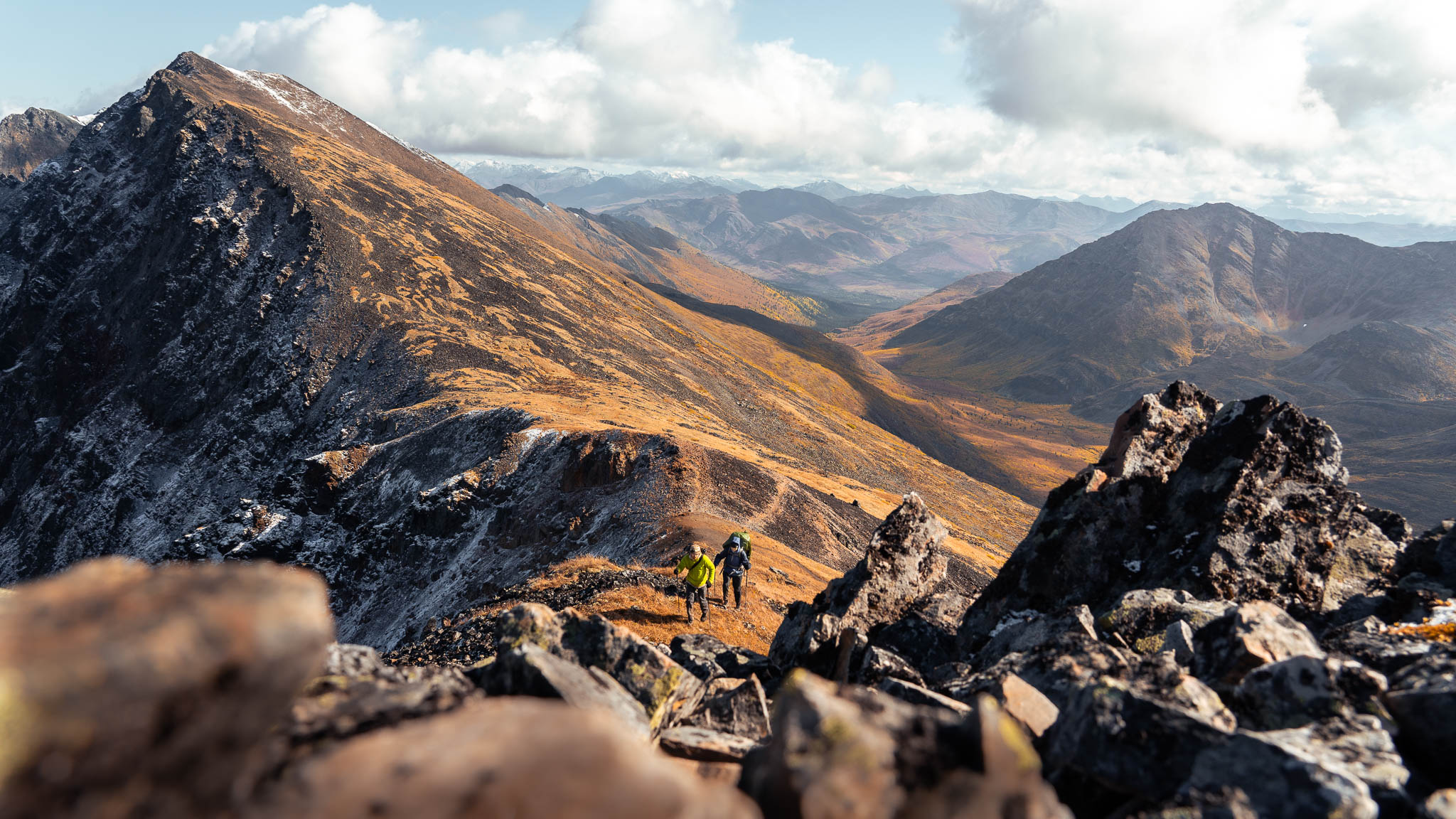 Two people hiking in the distance with huge mountain in background